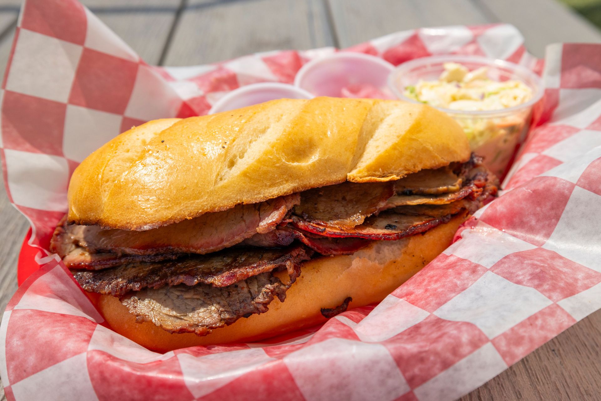 Mouthwatering brisket sandwich served in a red checkered basket with coleslaw on the side.